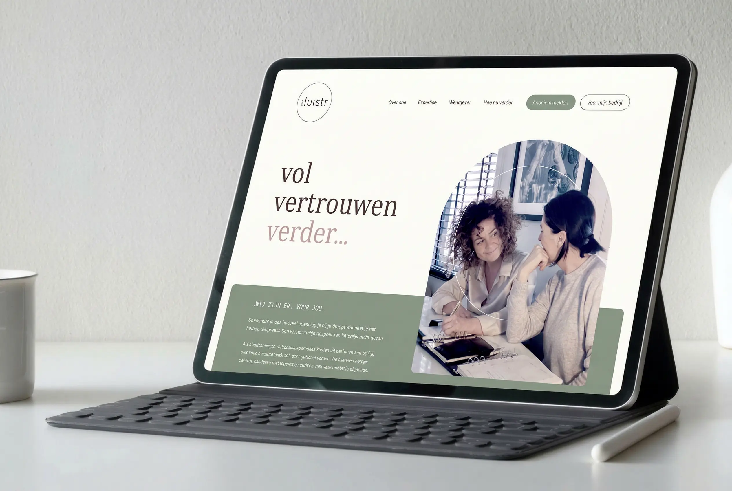 Tablet met website van Buro Luistr op een bureau met toetsenbord.