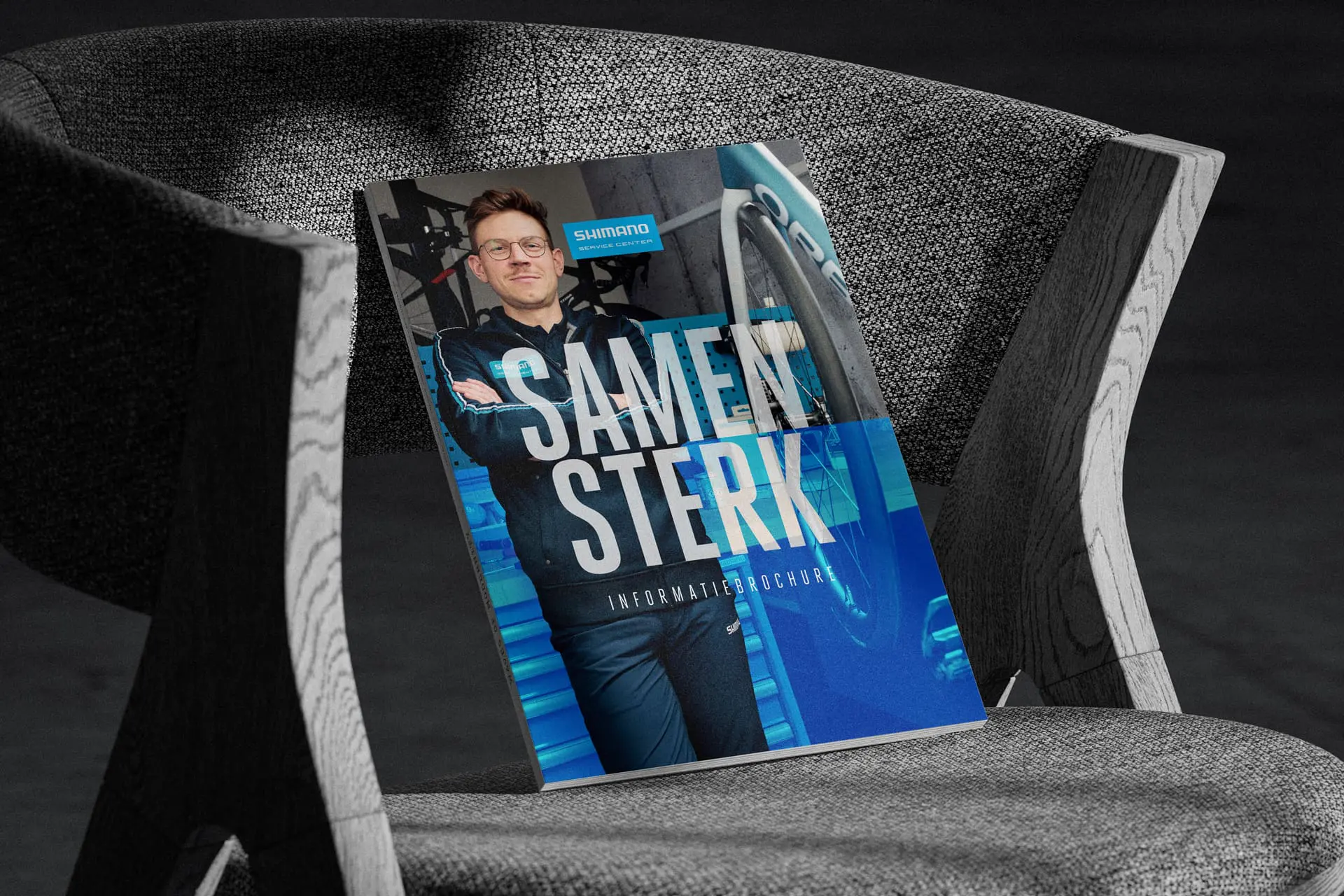 Shimano magazine met de titel “Samen Sterk” ligt op een grijze stoel.