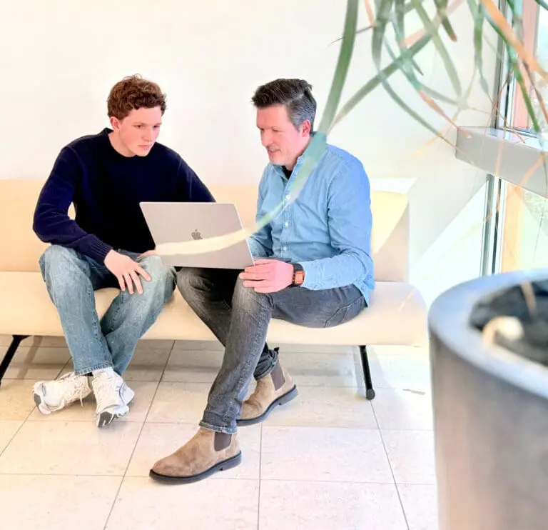 Twee collega's van Loeks overleggen met een laptop in een lichte kantoorruimte.