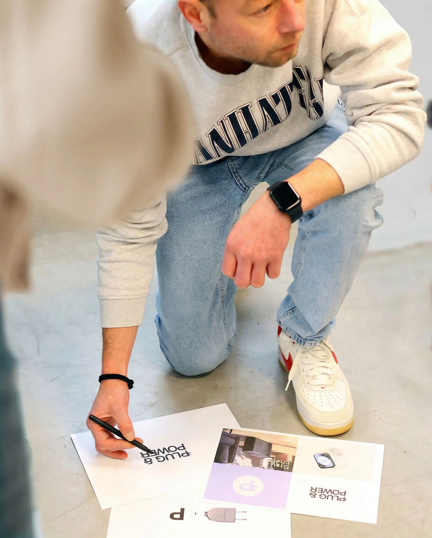 Eigenaar van LOEKS bekijkt ontwerpprints op de vloer en maakt aantekeningen met een pen.