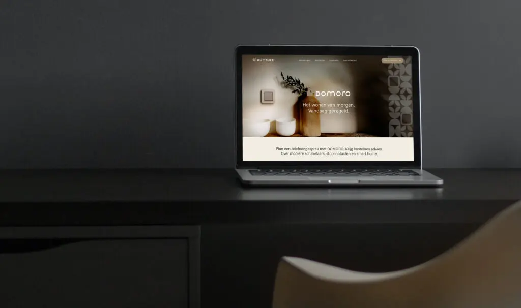 Laptop met Domoro website op donkere tafel.