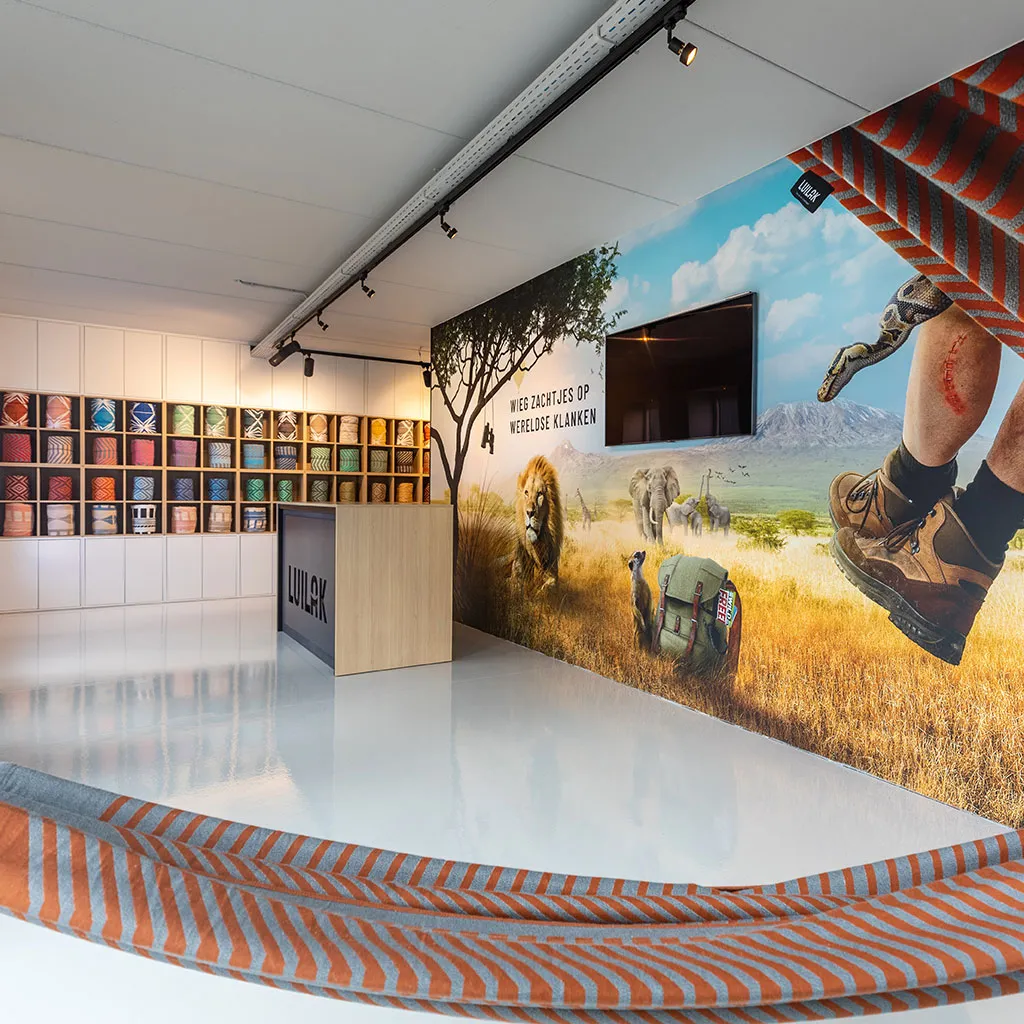 Ruime showroom met wandposter van een hangmat in de natuur en een presentatiebalie.