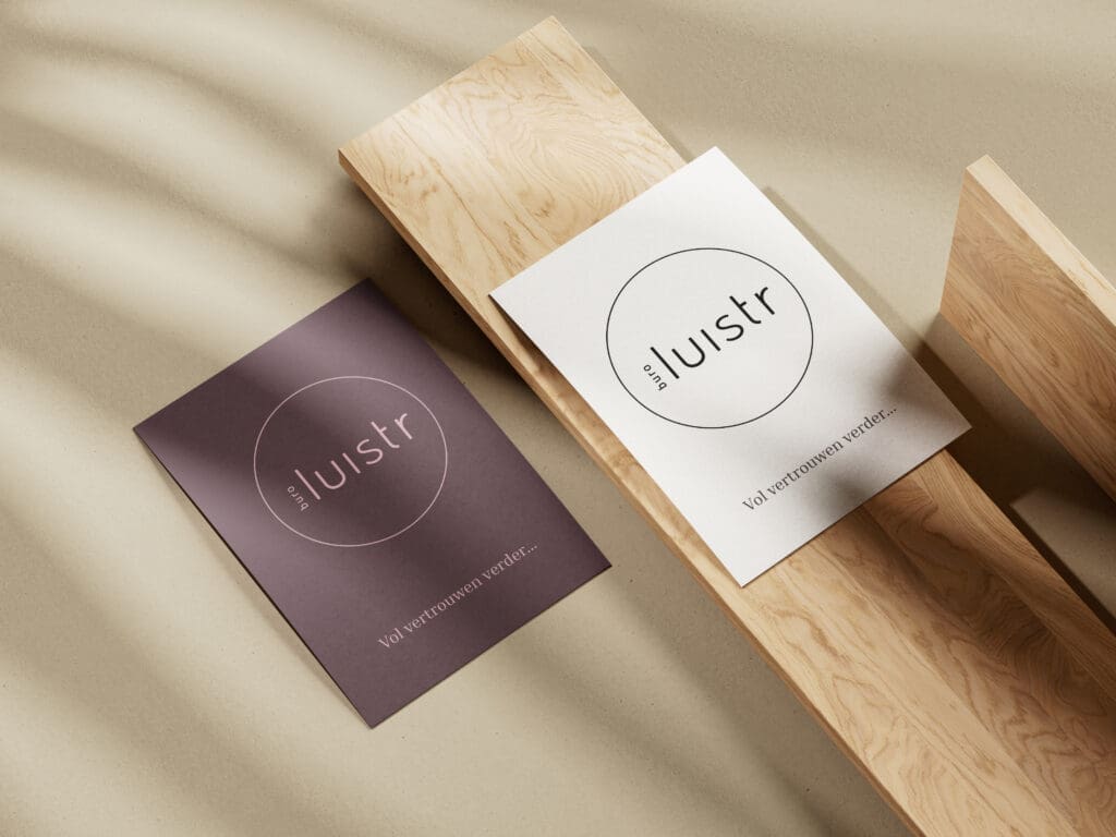 Twee visitekaartjes van Buro Luistr op een houten blok met zacht licht en schaduwen.