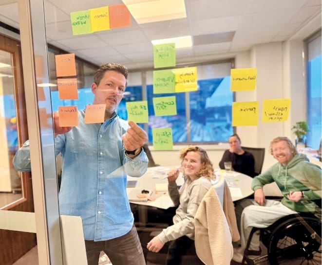 Loeks begeleidt een sessie bij een klant met post-its op een glazen wand.