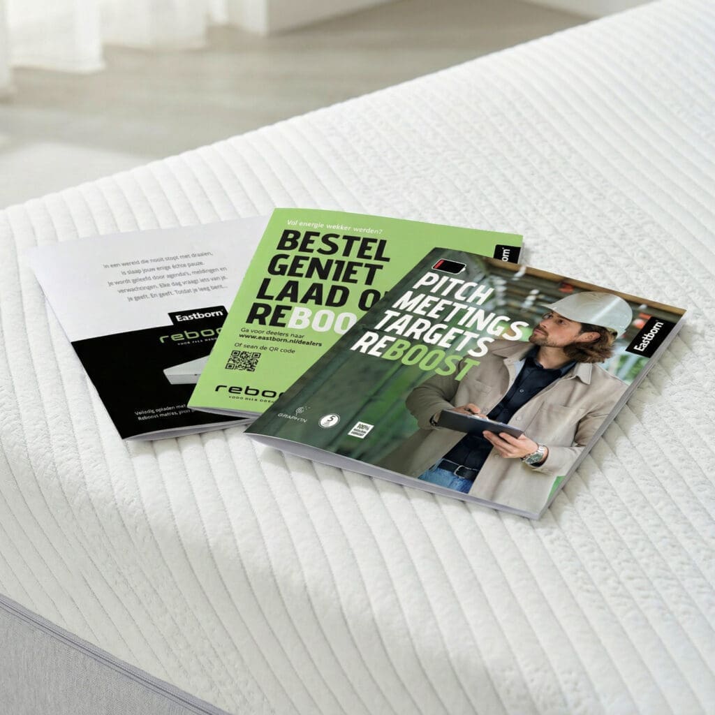 Open magazine met Reboost thema en kaarten op een wit bed met gestreepte stof.