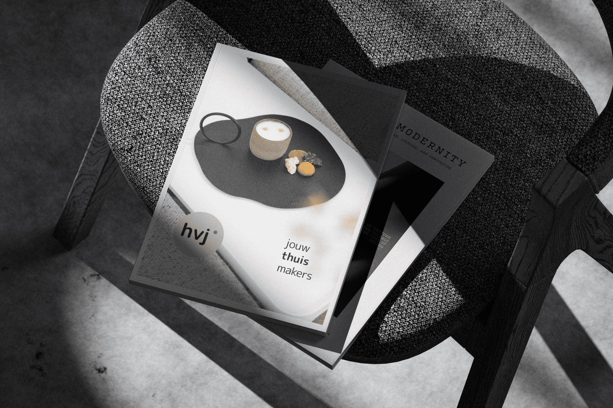 HVJ magazine met kopje koffie, bril en koekjes op een stoel in het zonlicht.