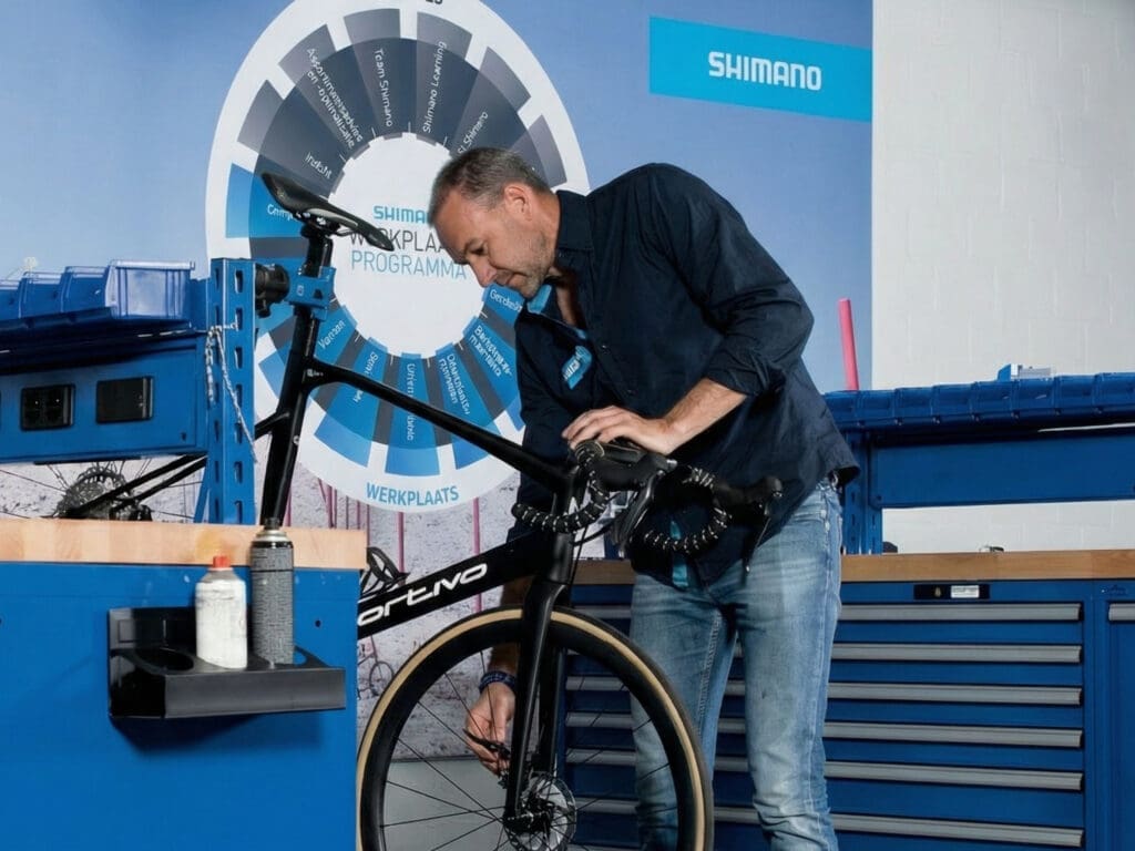 Fietsmonteur werkt aan een fiets in een werkplaats.