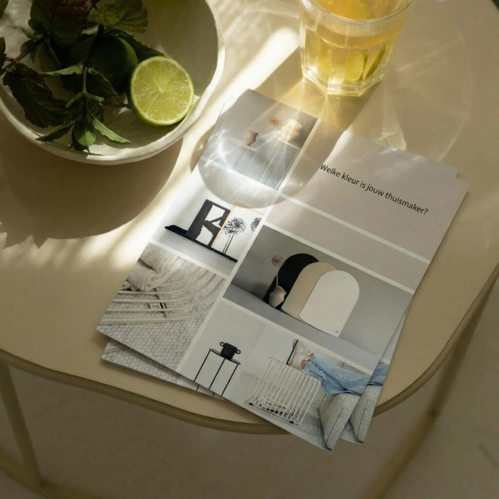 Interieurmagazine ligt op ronde tafel naast glas thee en schaaltje met limoen en munt.