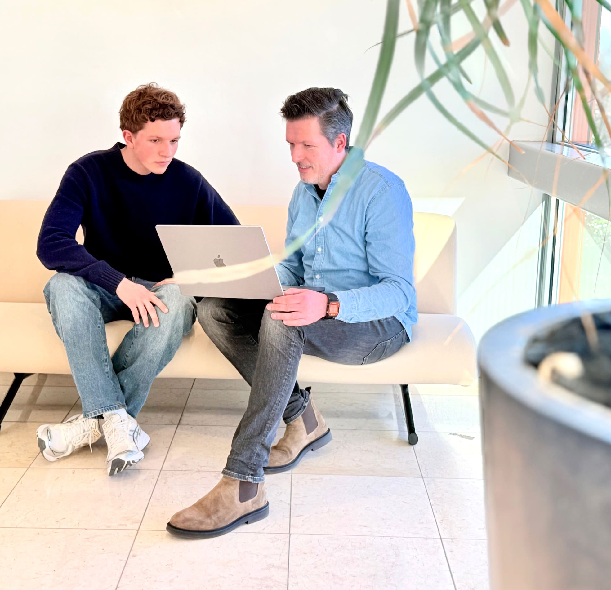 Twee collega's van Loeks overleggen met een laptop in een lichte kantoorruimte.
