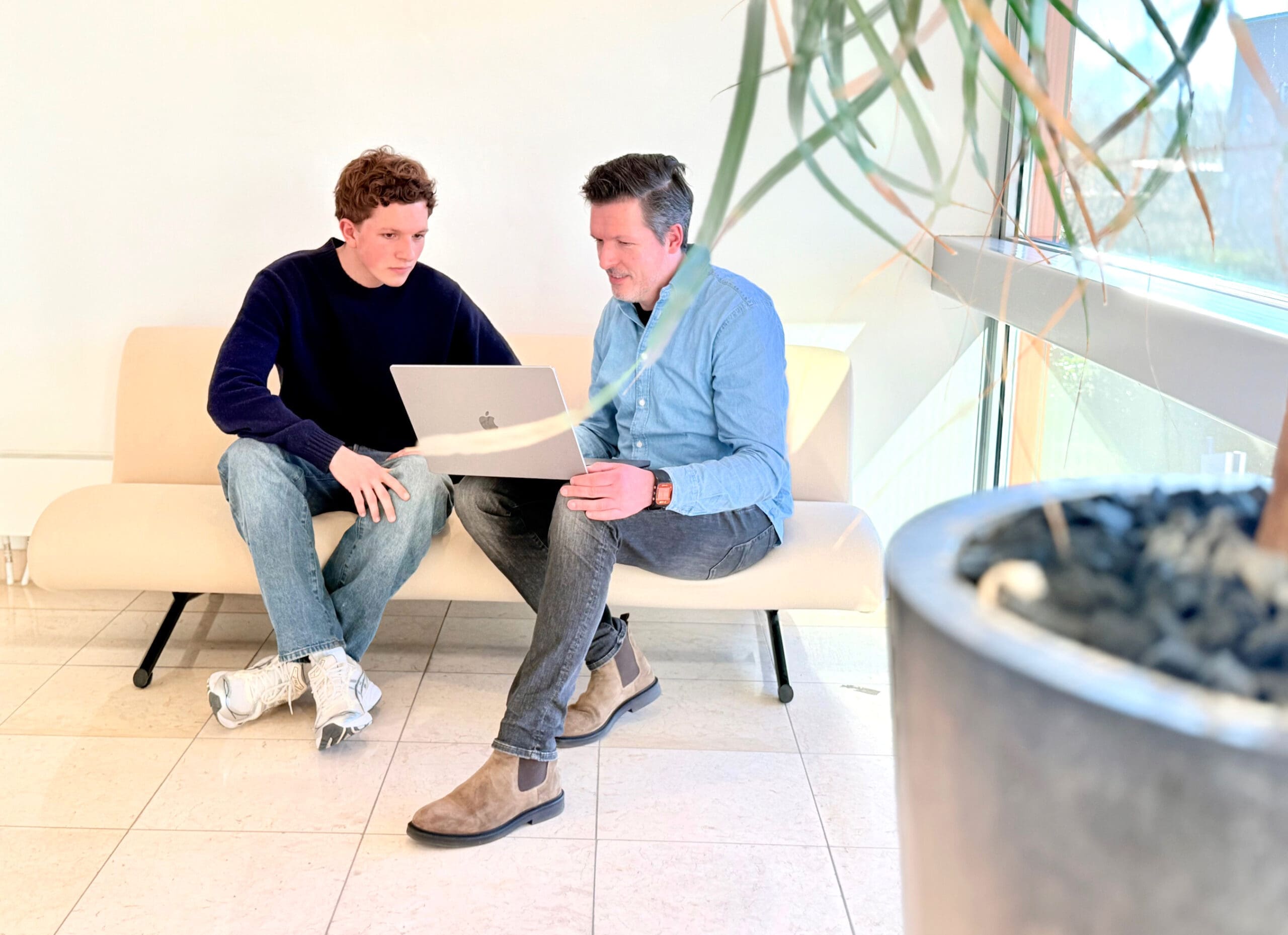 Twee collega's van Loeks overleggen met een laptop in een lichte kantoorruimte.