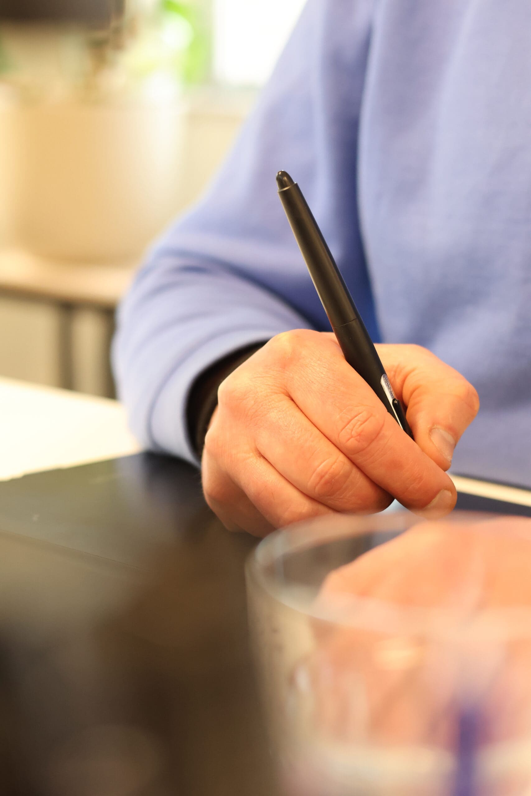Hand van de eigenaar van Loeks gebruikt een digitale pen op een tekentablet op een bureau.